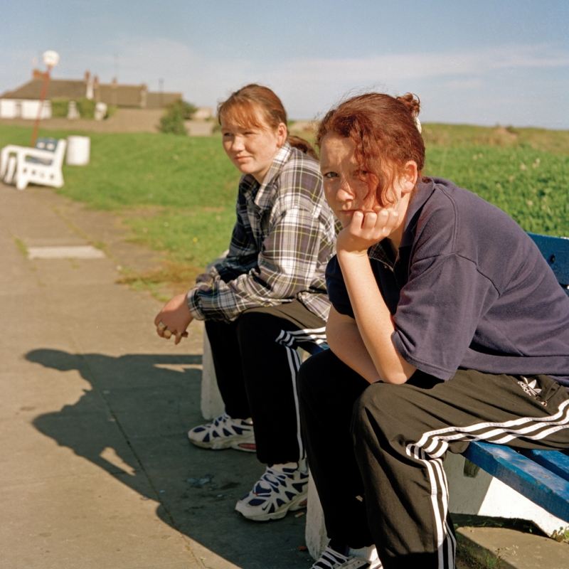 Girls sitting on a bench 
 from A Portrait of a Village by Kim Cunningham - Click for Next Image